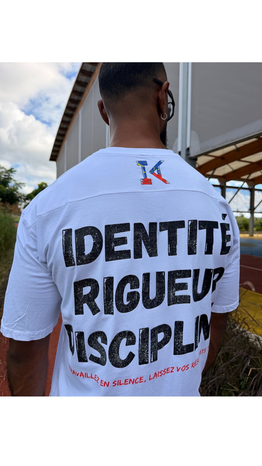 T-shirt blanc oversize KRÉOL ATHLETIC avec inscription noire "IDENTITÉ RIGUEUR DISCIPLINE" et logo 974 au dos.